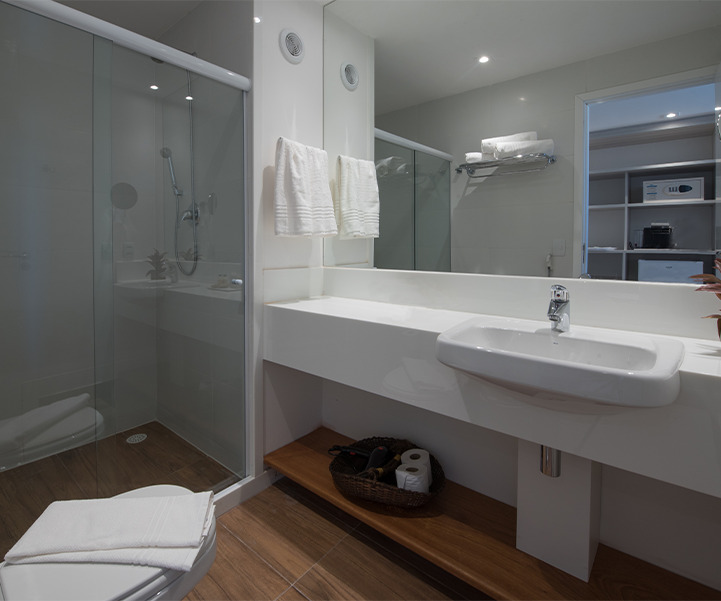 Banheiro do Quarto Standard, com pia moderna, box de vidro e iluminação suave.